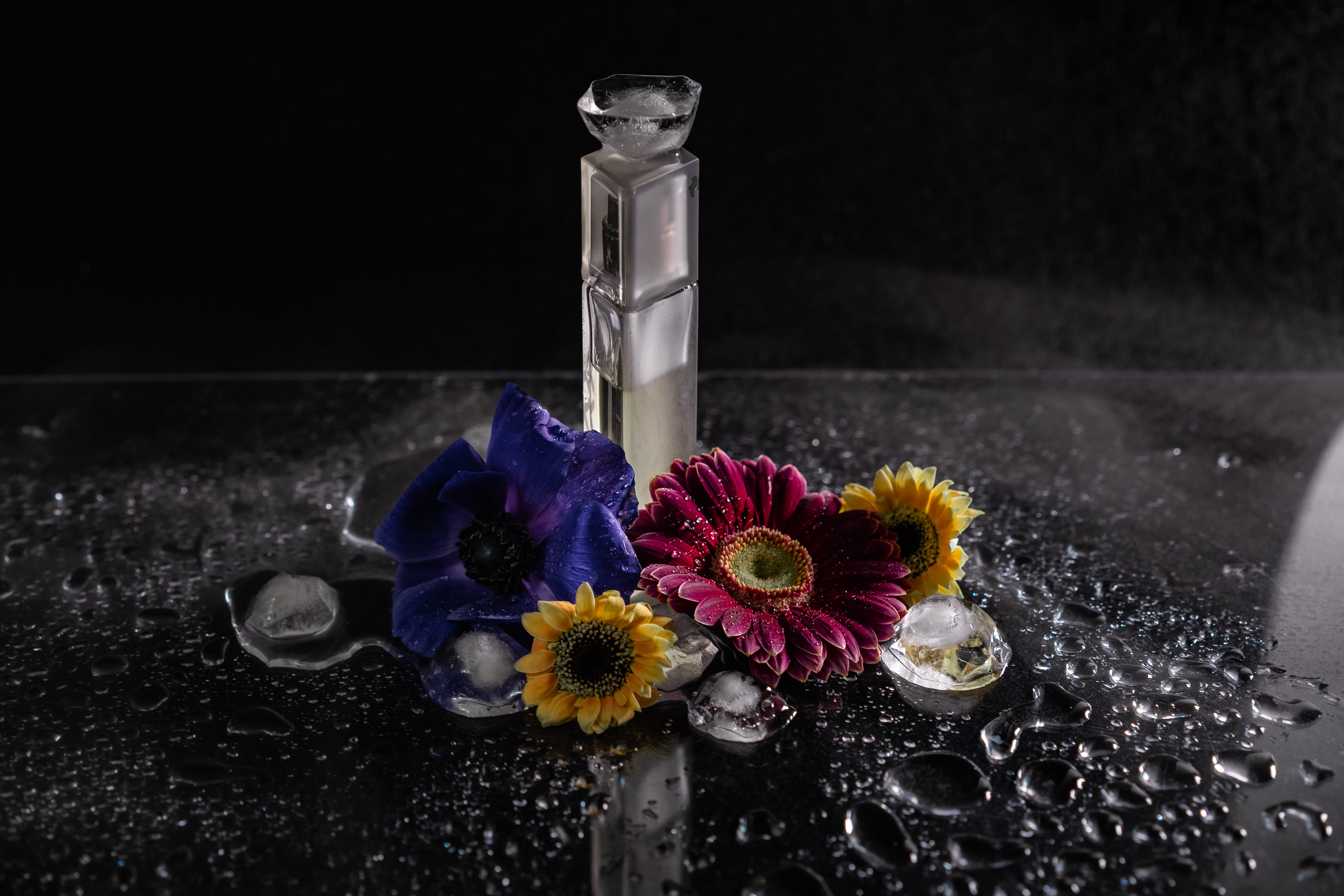 a glass bottle placed between four flowers in front of a foggy background